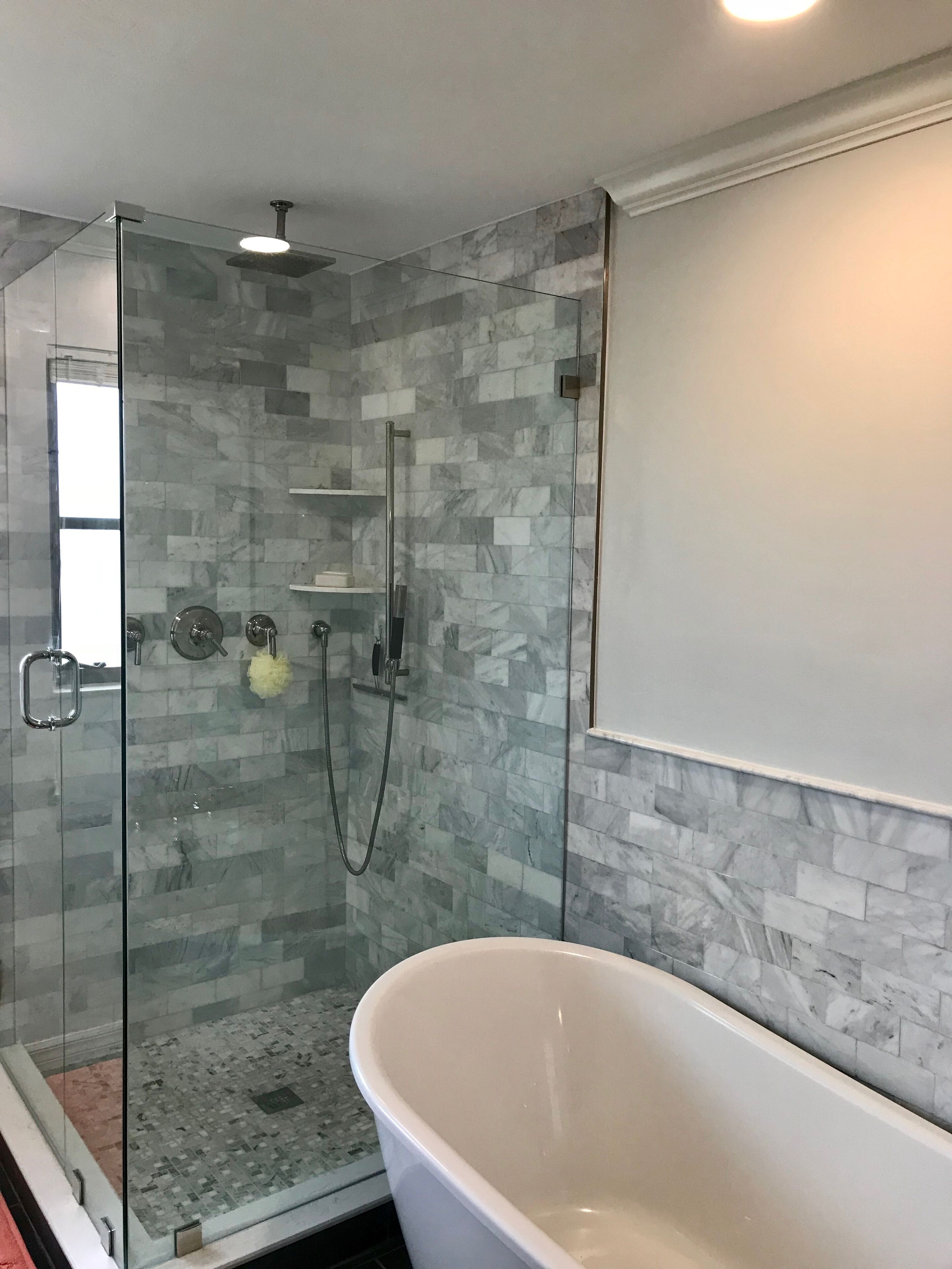 A modern bathroom with a glass-enclosed shower, a freestanding bathtub, and a tiled shower wall.