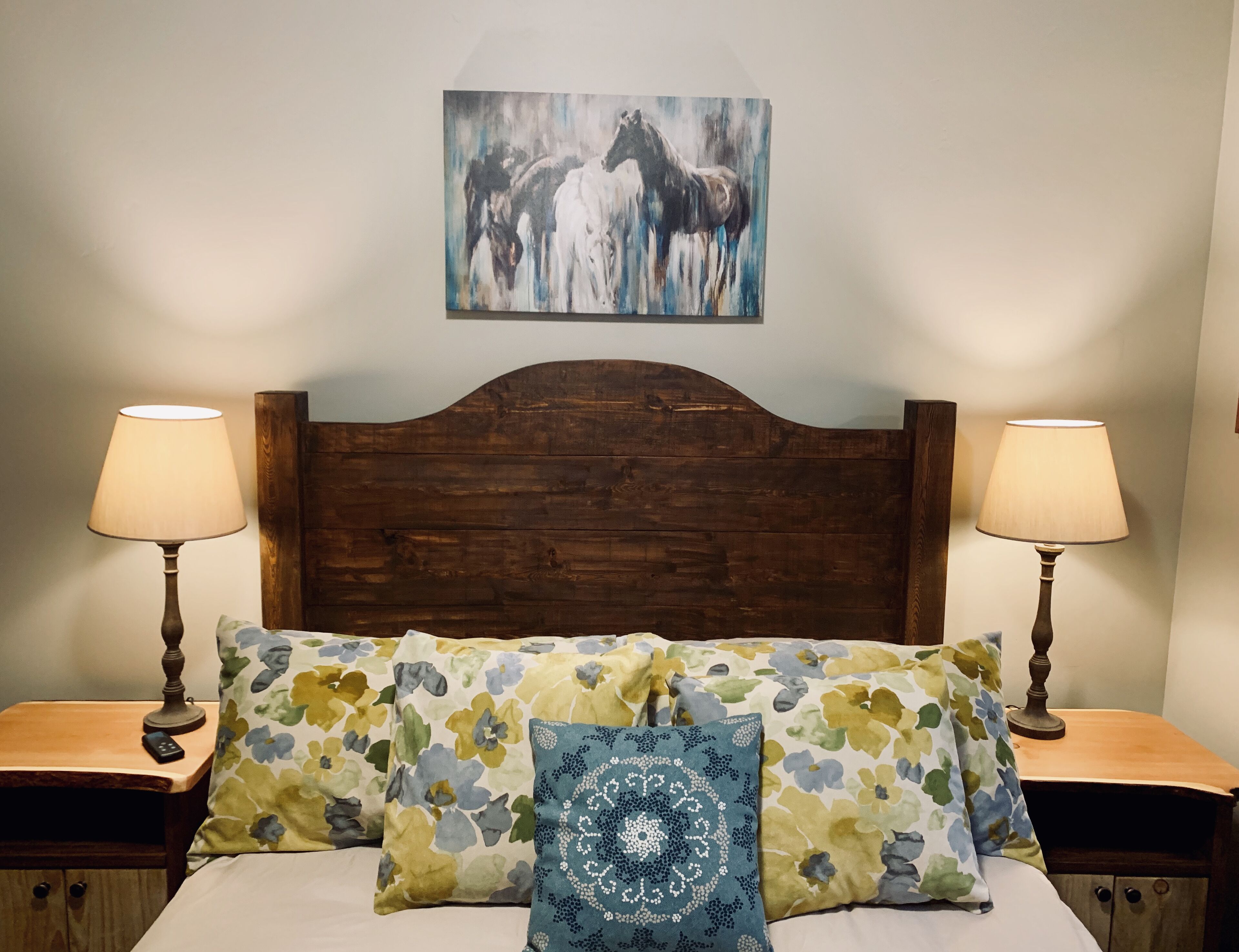 A bed with floral-patterned pillows, a wooden headboard, and two bedside lamps.