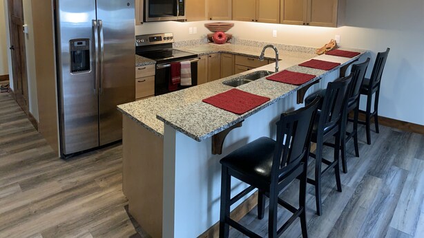 Een moderne keuken met een centraal eiland, roestvrijstalen apparatuur en houten vloeren.