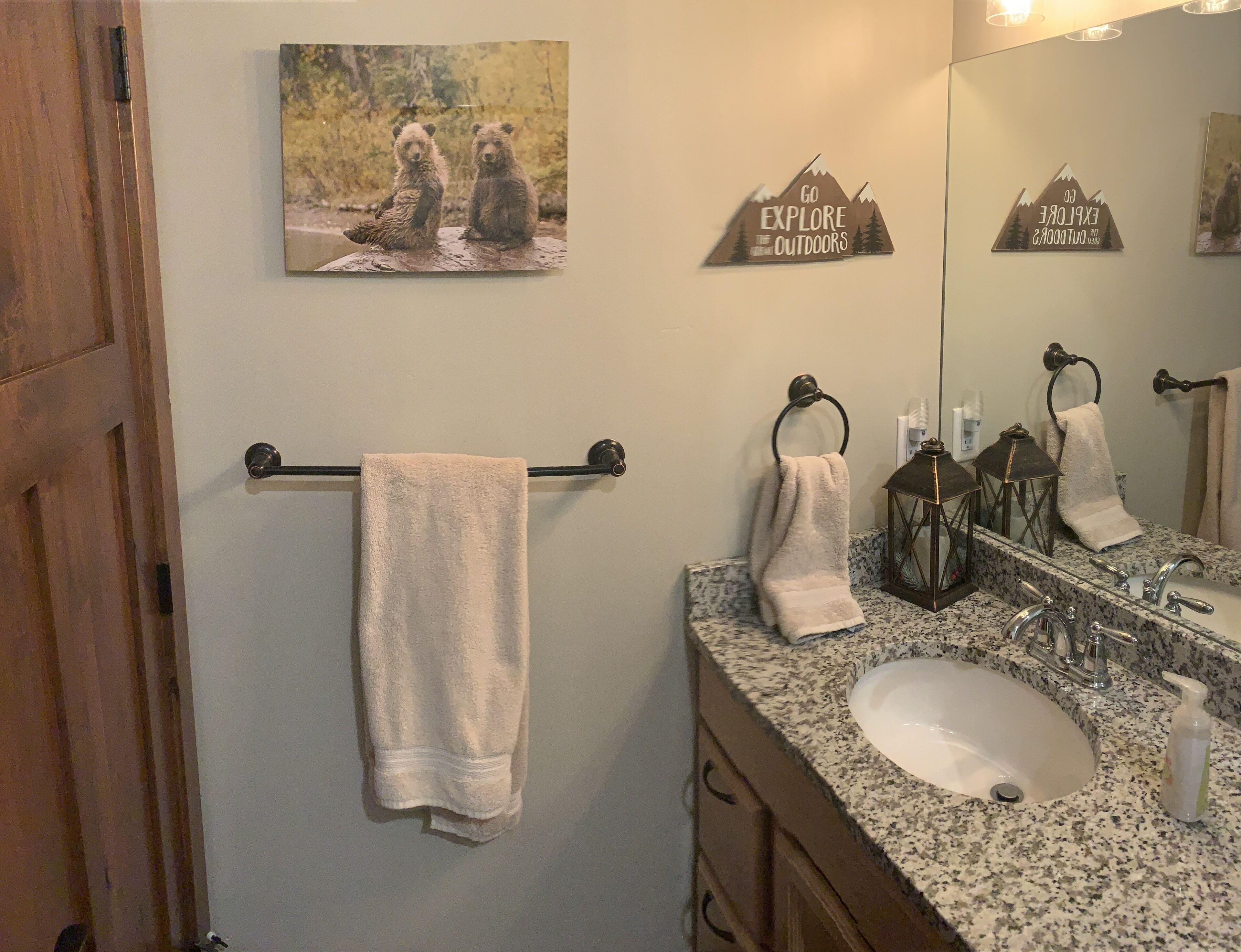 A bathroom with a granite countertop sink, a mirror, and two towels hanging on a towel rack.