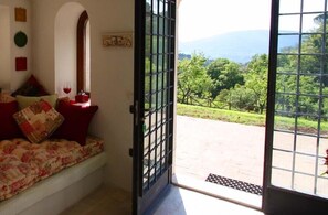 Ein Zimmer mit Blick auf einen üppigen Garten und Berge.