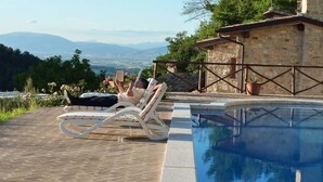 Un espace aménagé au bord de la piscine, avec un fauteuil de relaxation et une vue sur le paysage.