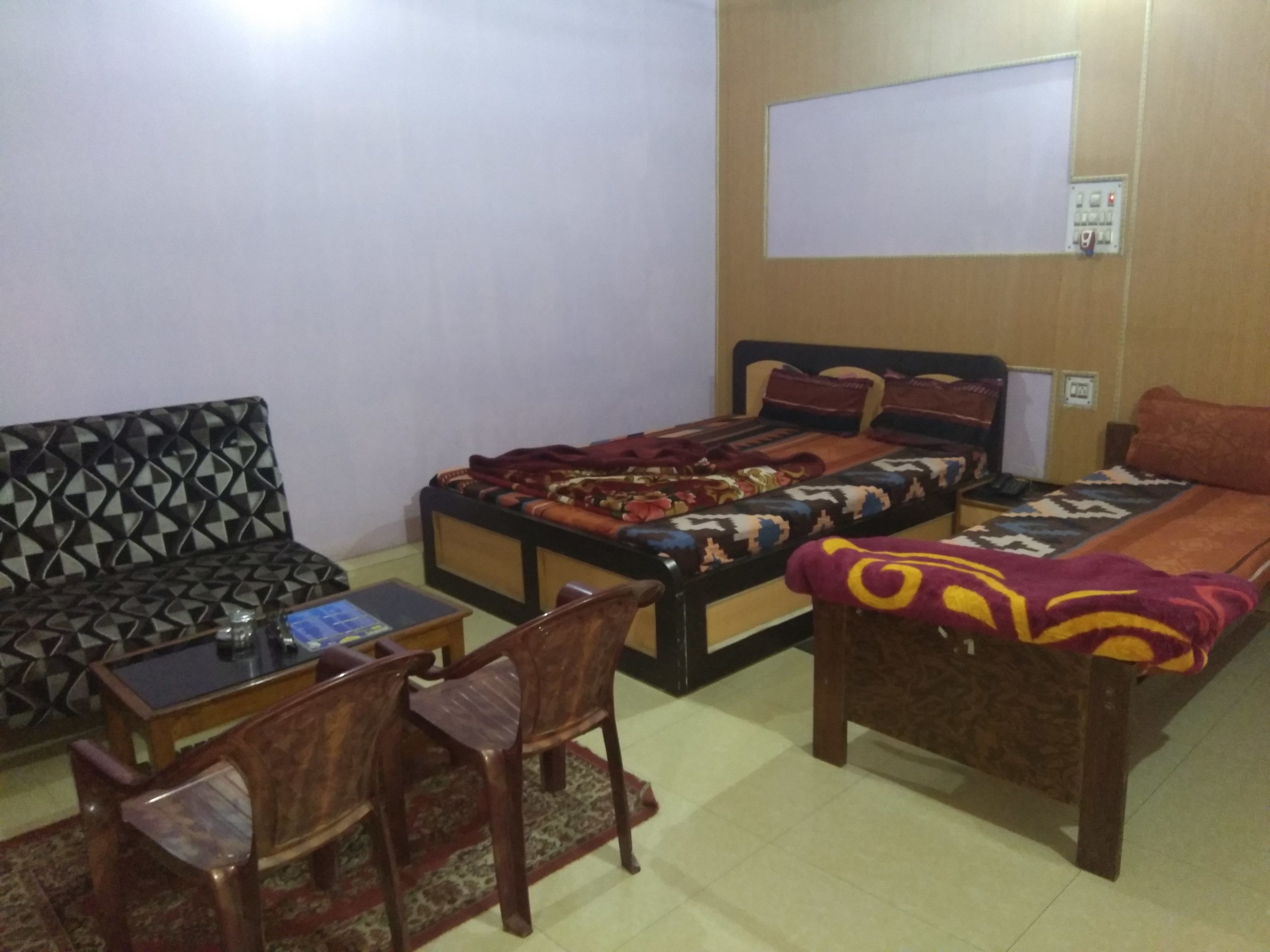 A room with a bed, a sofa, a small table, and a chair.