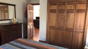 Un dormitorio con cama, cómoda, armario y espejo.