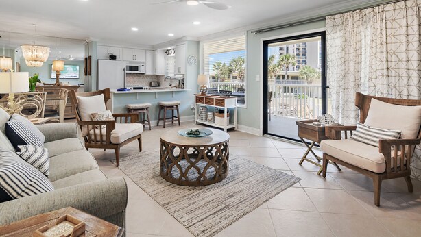 A spacious living area with a sofa, chairs, a coffee table, and a kitchen in the background.