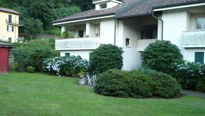 A two-story building with a balcony, surrounded by well-maintained lawns and bushes. - cozy attic in Dervio (dervio)