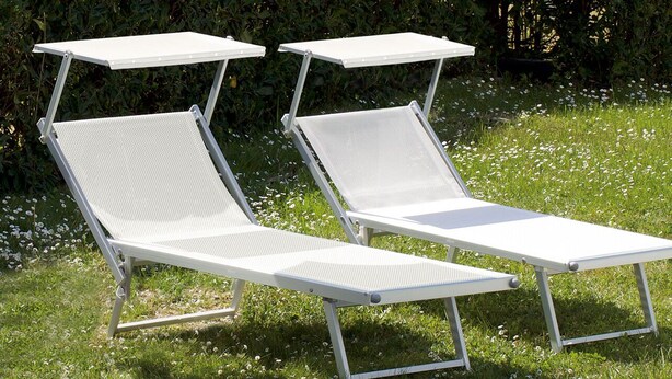 Two white sun loungers with metal frames and mesh backs, positioned on a grassy area with white flowers. - cozy attic in Dervio (dervio)