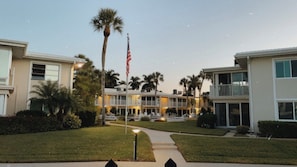 A hotel with a pool, palm trees, and an American flag.