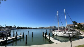 Un port de plaisance où sont amarrés des voiliers, un ciel bleu dégagé et des bâtiments en arrière-plan.