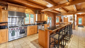 A spacious log cabin kitchen with a central island, stainless steel appliances, and wooden cabinetry. - Luxury Log Cabin Near Cascade Lake, 80 Acres, RVs (Cascade)