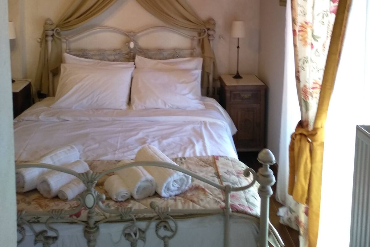 Ein Schlafzimmer mit Bett, Vorhängen und Nachttisch.