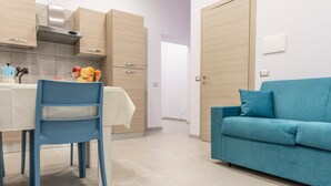 A modern kitchen with wooden cabinets and a blue chair. - Casina Rossa Apartment Procida (Napoli)