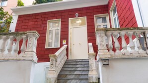 A red building with a white door and a staircase leading to the entrance. - Casina Rossa Apartment Procida (Napoli)