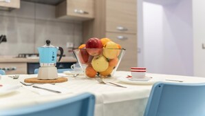 A kitchen with a coffee maker, a bowl of fruit, and a cup on the table. - Casina Rossa Apartment Procida (Napoli)