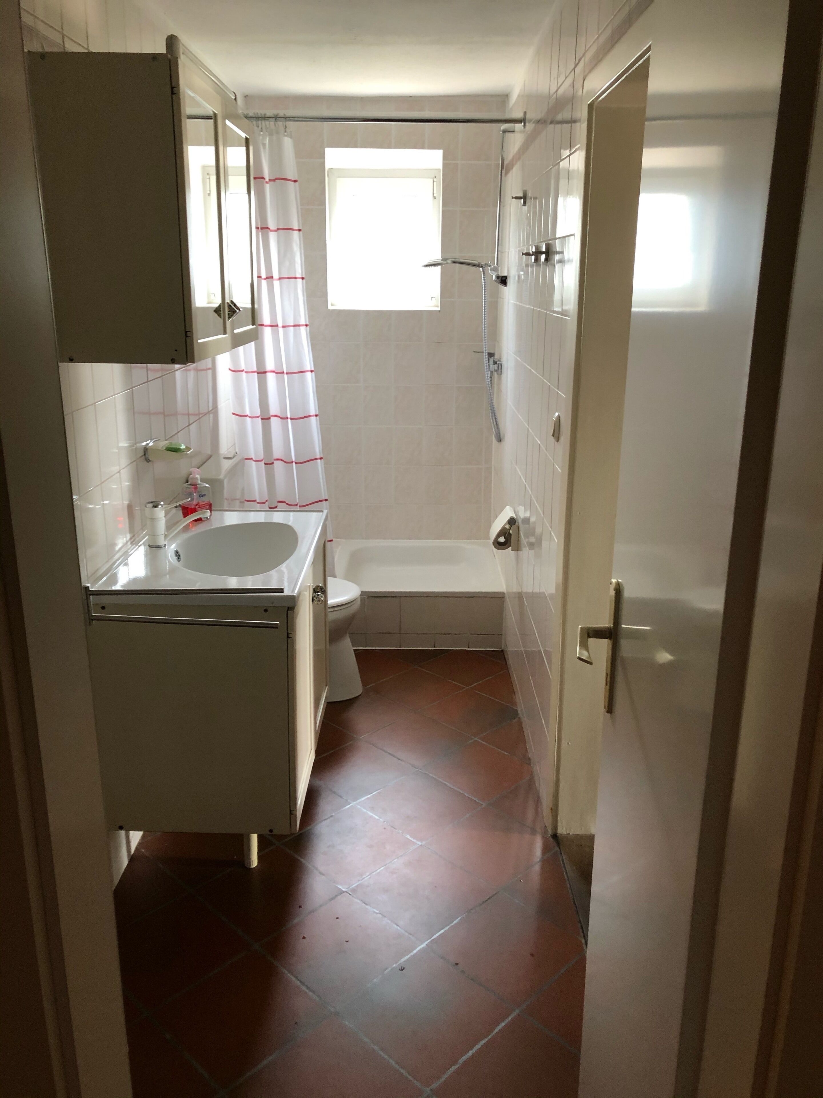 A compact bathroom with a toilet, sink, and shower area.