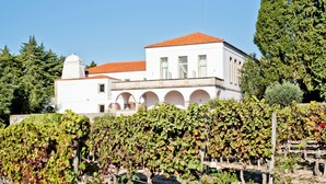 A white building with a red-tiled roof and arched windows, surrounded by vineyards. - Lam Hotel Convento do Desagravo (Oliveira do Hospital)