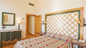 Un dormitorio con una cama, un aparador de madera, una mesita de noche y una lámpara de pared.