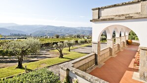 A vineyard with rows of grapevines, a stone building with arches, and a mountainous backdrop. - Lam Hotel Convento do Desagravo (Oliveira do Hospital)