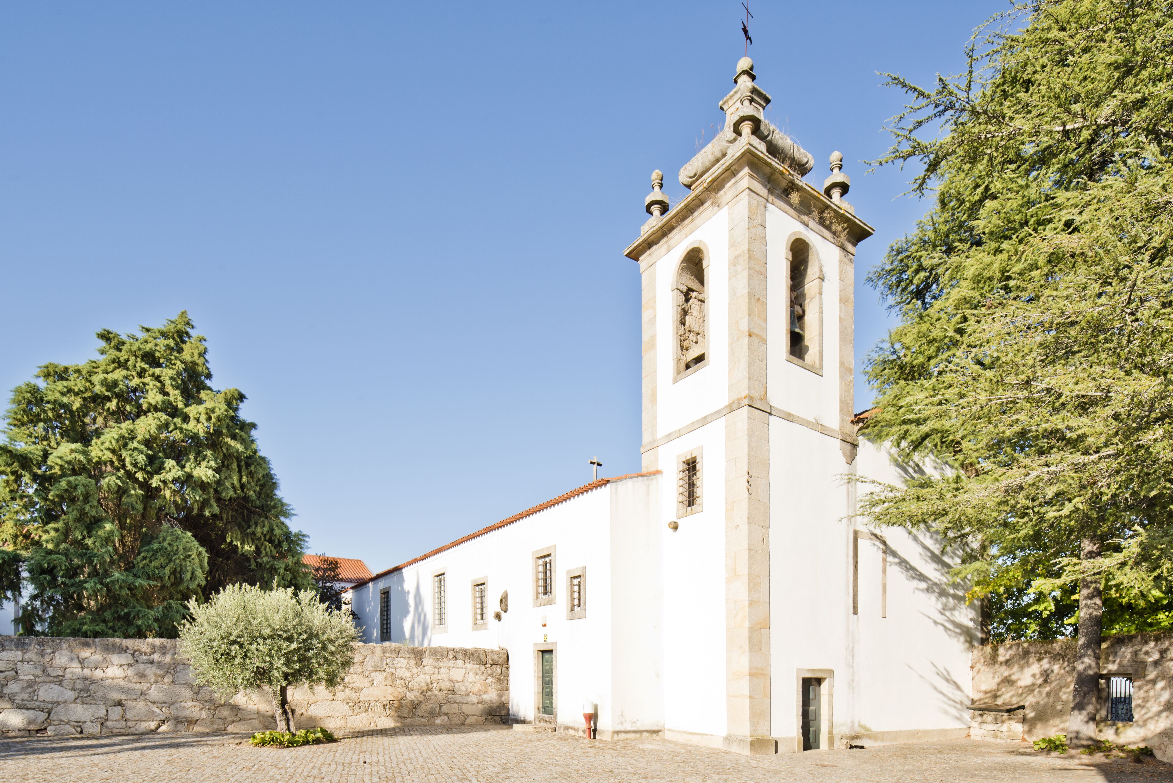A historic building with a bell tower, stone walls, and a cobblestone courtyard.