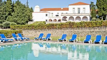 Una piscina al aire libre de temporada, sombrillas