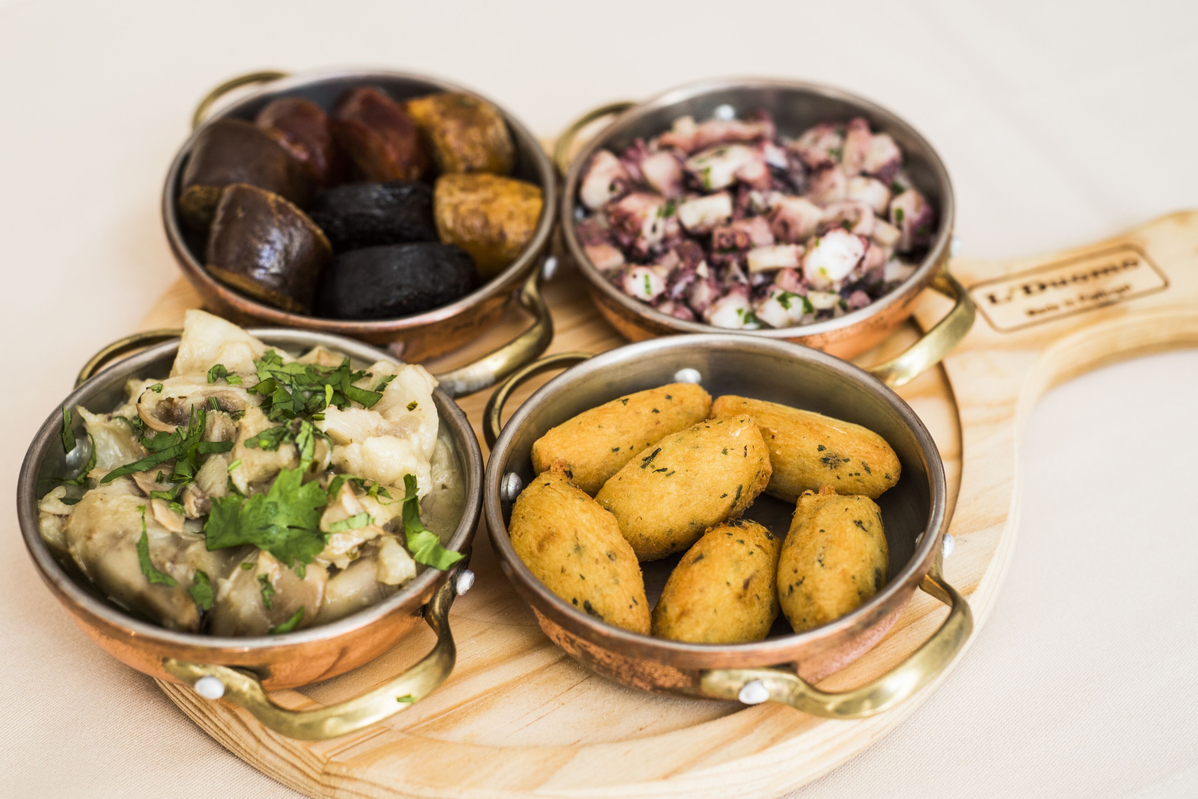 Four metal bowls containing different food items on a wooden board.