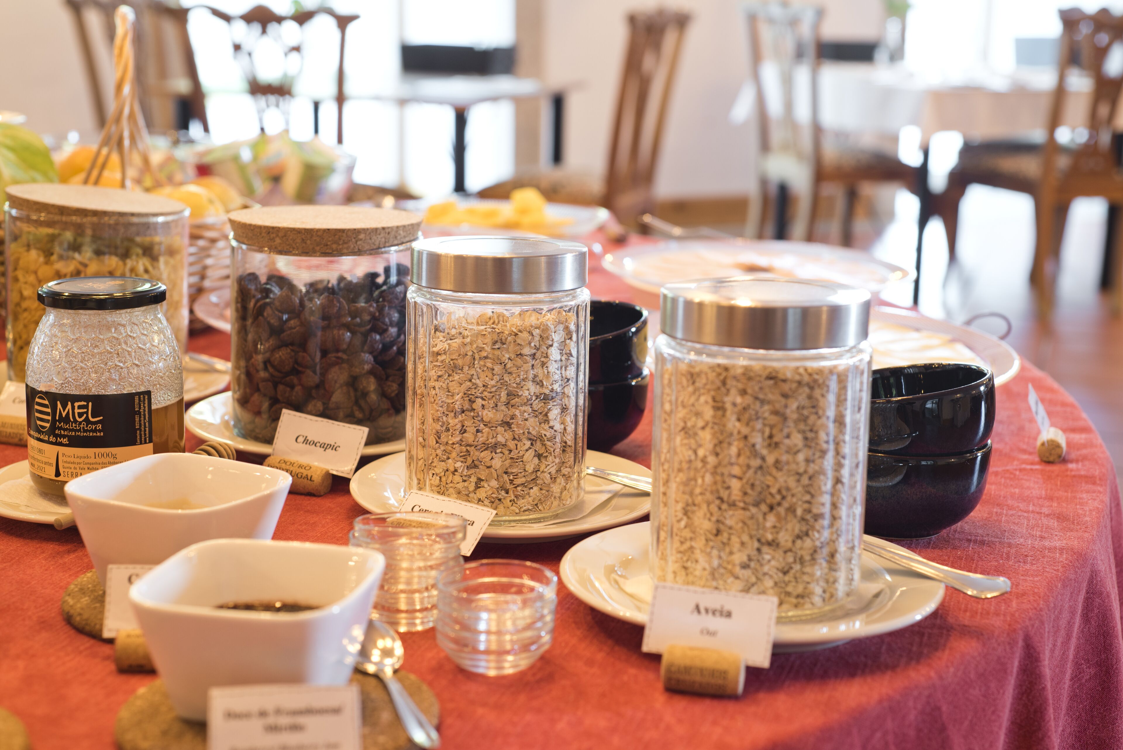 Una mesa con diversos alimentos y recipientes, incluyendo frascos con nombres como 'Chocopic' y 'Avelia'.
