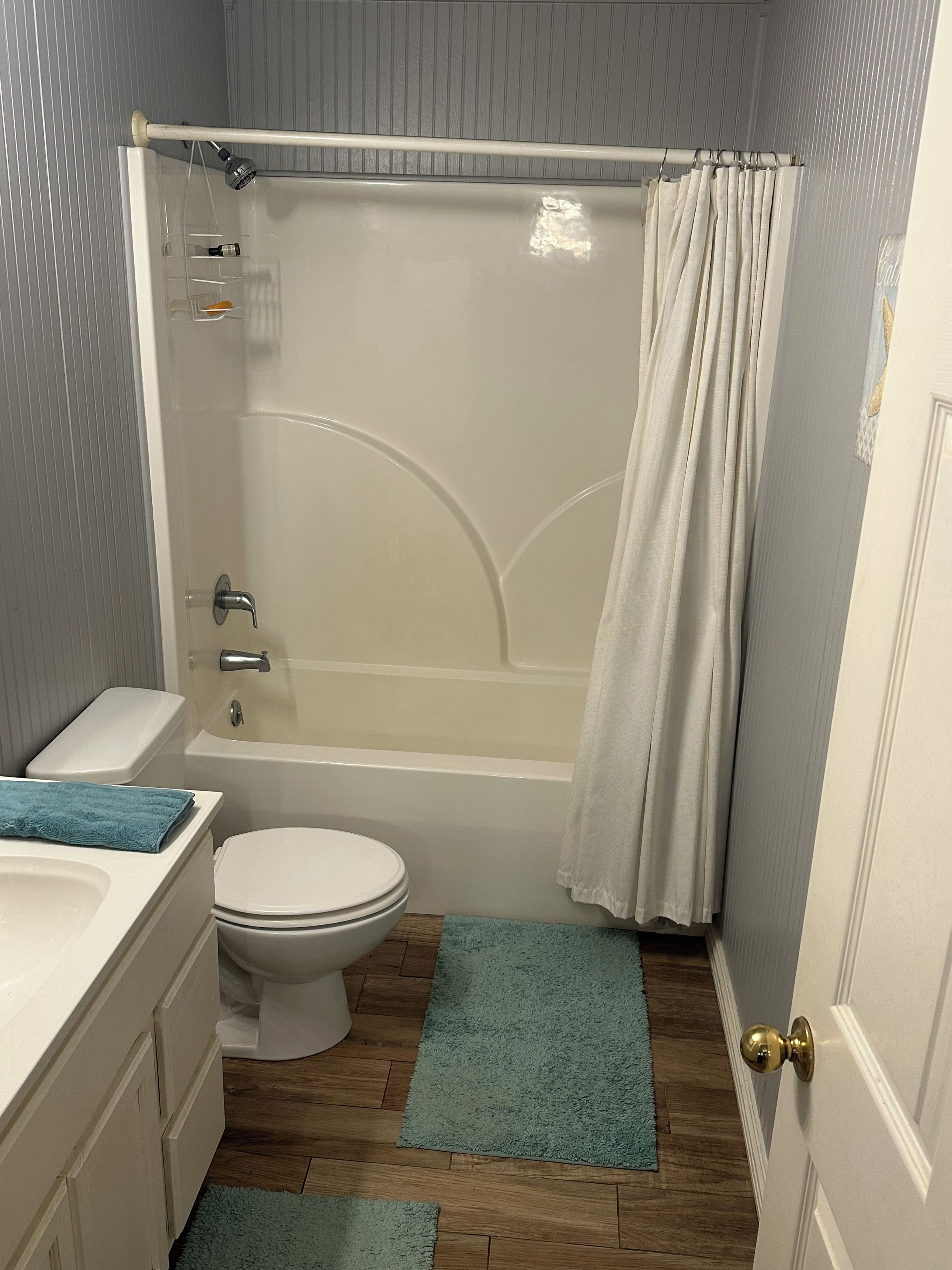 A bathroom with a bathtub, toilet, sink, and a shower curtain.