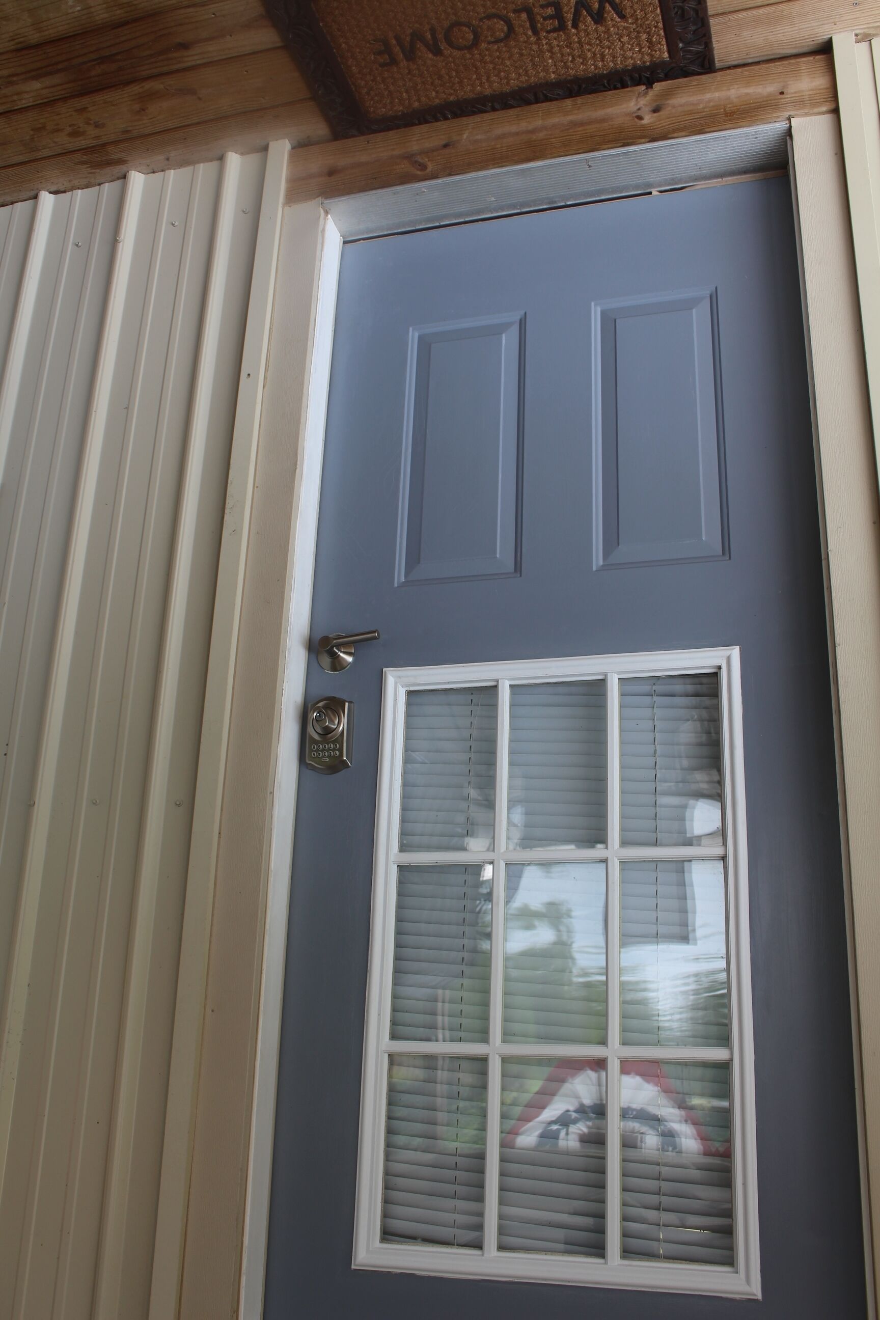 A front door with a window, a doorbell, and a mailbox.
