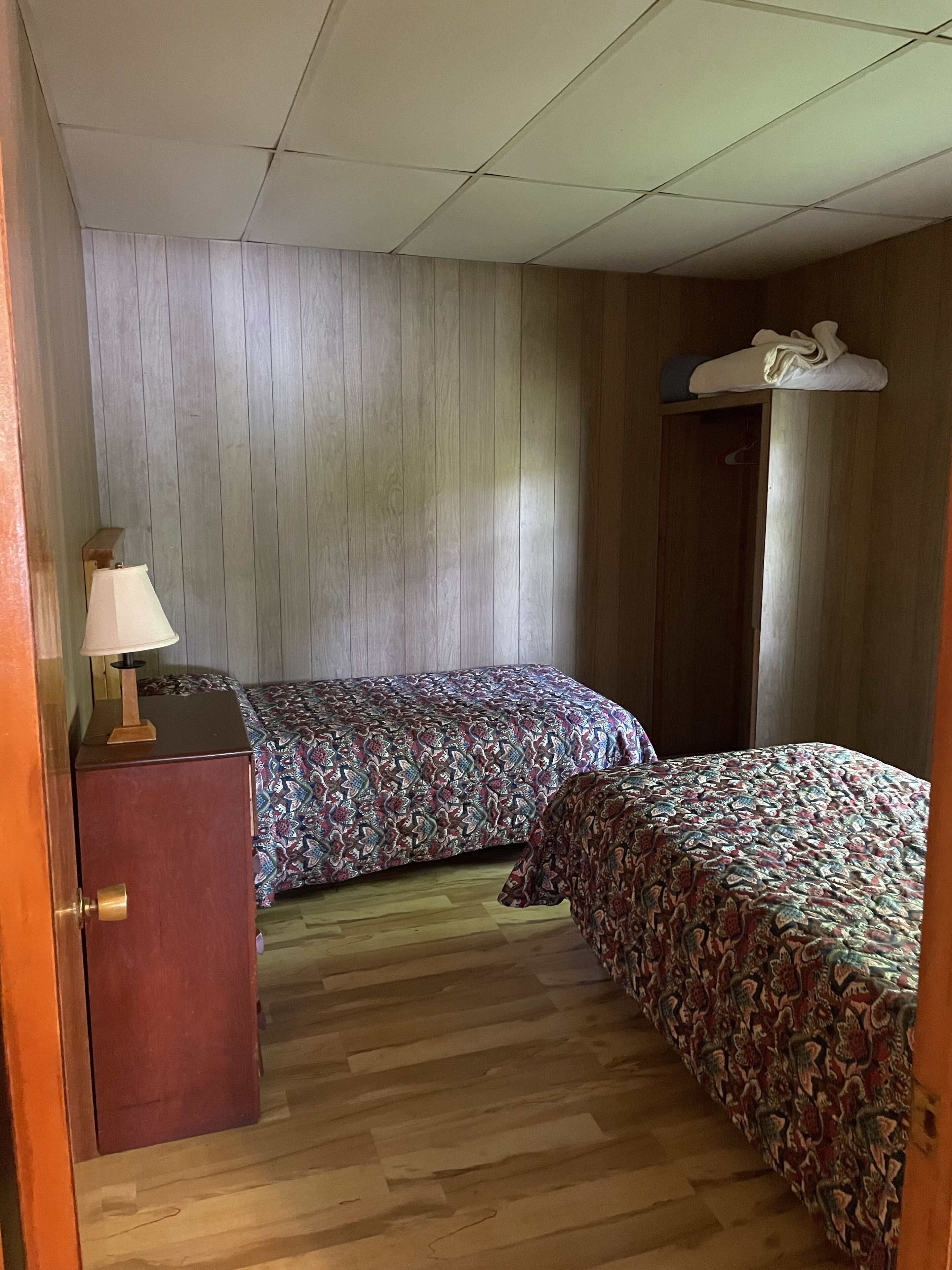 Una stanza con due letti, un'armadio in legno e un soffitto con un lampadario.