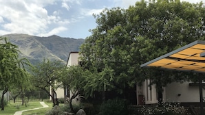A house with a gravel driveway, surrounded by trees and a mountain in the background.