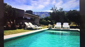 A swimming pool with two lounge chairs and a hot tub.