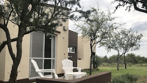 A building with a patio area featuring two white chairs and a table.