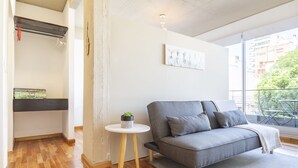 A modern living room with a grey sofa, a small round table with a plant, and a view of the city through large windows. - Fitz Roy by Be Local Argentina (Buenos Aires)