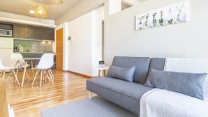 A modern living room with a grey sofa, wooden flooring, and a kitchen in the background. - Fitz Roy by Be Local Argentina (Buenos Aires)