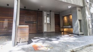 A modern building entrance with a metal gate, a bench, and a stone wall with a planter. - Fitz Roy by Be Local Argentina (Buenos Aires)