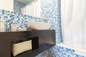 A bathroom with a white sink, blue mosaic tiles, and a dark countertop.