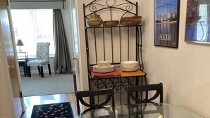 A dining area with a glass table, black chairs, and a metal shelf with plates. - 50's Classic: Cozy, convenient, comfortable (St Louis)