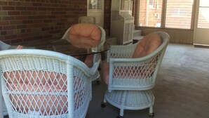 A room with wicker furniture, a glass table, and a view through large windows. - 50's Classic: Cozy, convenient, comfortable (St Louis)
