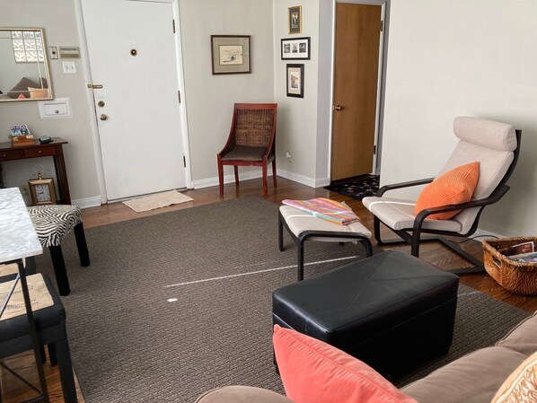 A living room with a sofa, armchair, ottoman, and a small table with a clock. - 50's Classic: Cozy, convenient, comfortable (St Louis)