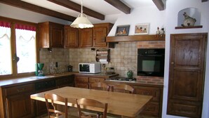 Una cocina con armarios de madera, una isla central con sillas, un microondas, una estufa y un fregadero.