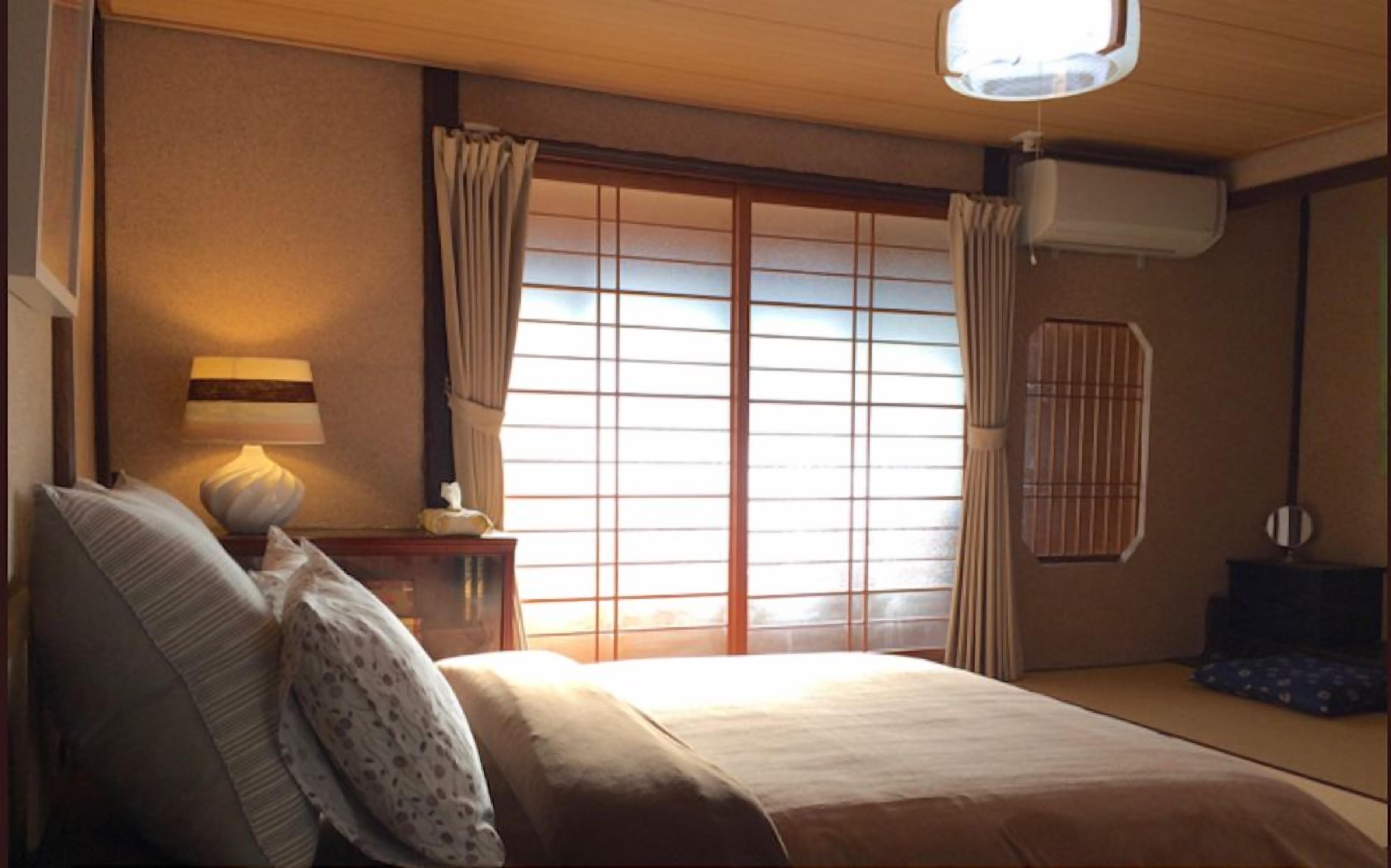 Une chambre d’hôtel avec un lit, une table de chevet avec une lampe et une fenêtre avec des rideaux.