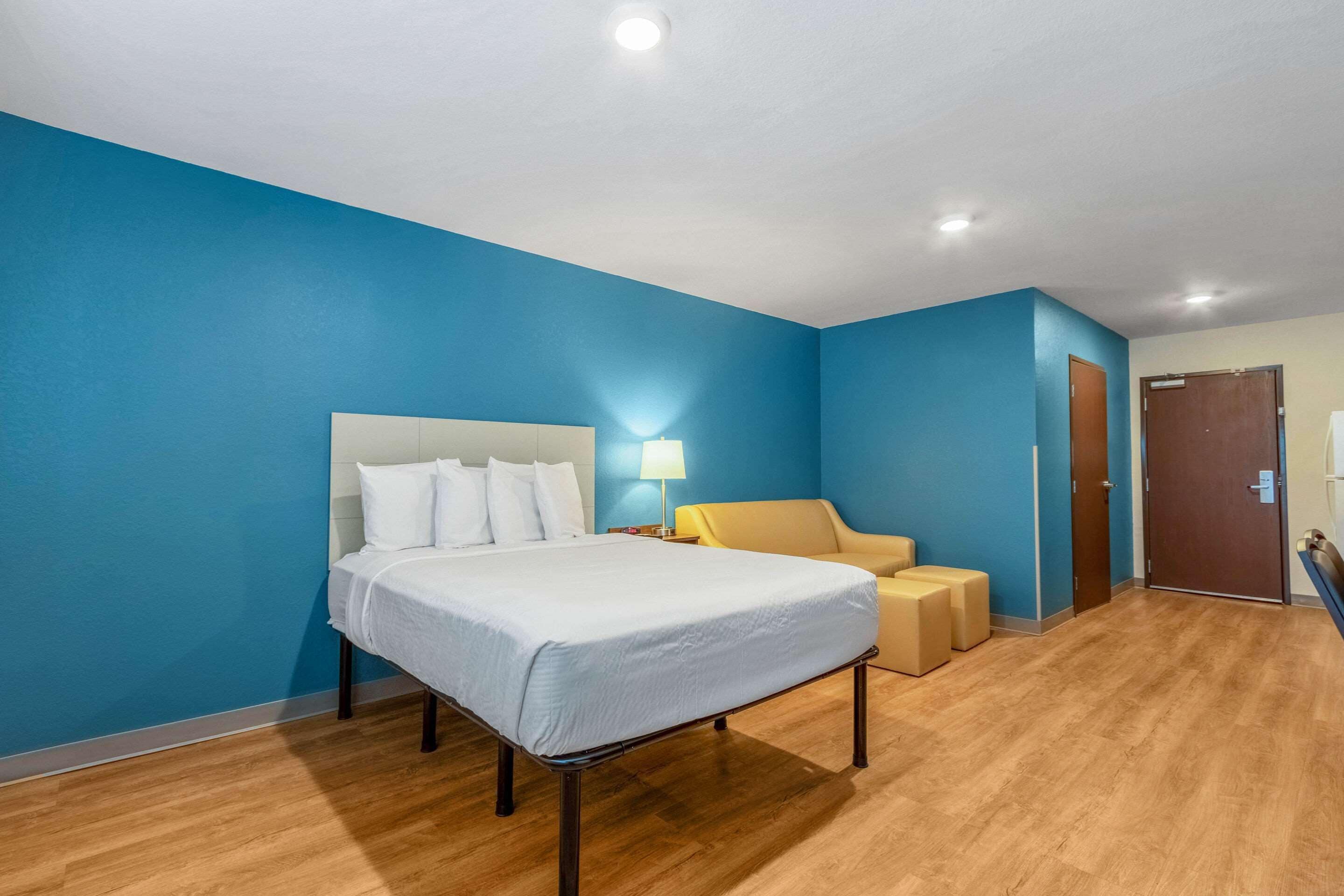 A hotel room with a bed, a nightstand, a lamp, and a chair.