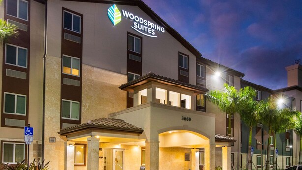Ein Hotel mit einem Schild mit der Aufschrift 'Woodspring Suites' und einem barrierefreien Eingang.
