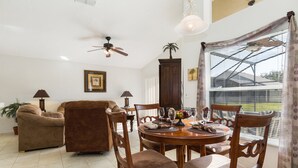 Un coin repas avec une table ronde, des chaises en bois et un ventilateur de plafond.