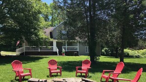 Quintal com lareira e quatro cadeiras Adirondack vermelhas.