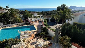 Ein Poolbereich mit Liegestühlen, einer Springbrunnen und Blick auf das Meer.