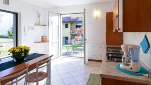A kitchen with a dining area, a view of the outside, and a coffee maker. - Lake Como - Residence La Collina - Pera (Vercana)