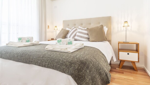 A neatly made bed with a grey textured bedspread, two pillows, and a bedside table with a lamp. - Lafinur by Be Local Argentina (Buenos Aires)