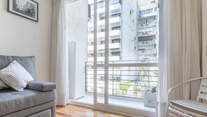 A modern living room with a grey sofa, a small table, and a view of a residential building through a large window. - Lafinur by Be Local Argentina (Buenos Aires)
