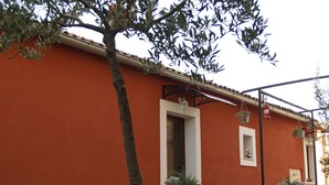 A building with a red exterior, a door, and a small garden area with potted plants. - Provvidenza (Motovun)